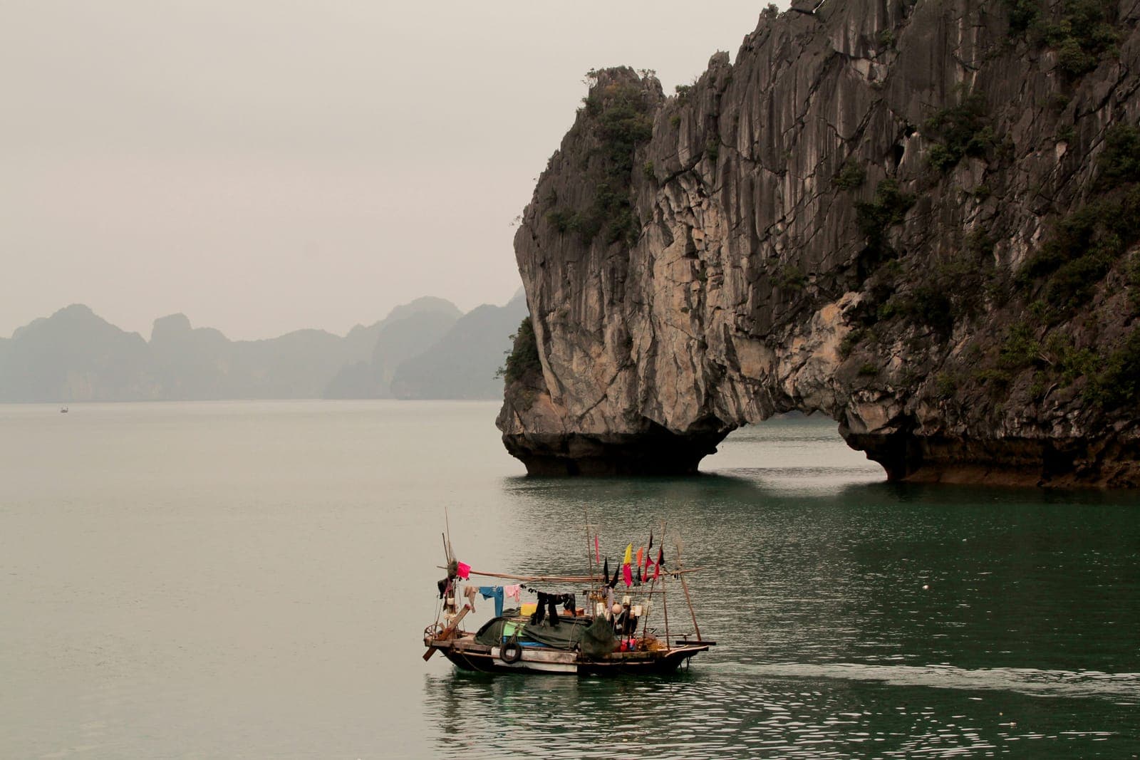 A boat sailing past limestone karst islands in Ha Long Bay, Vietnam