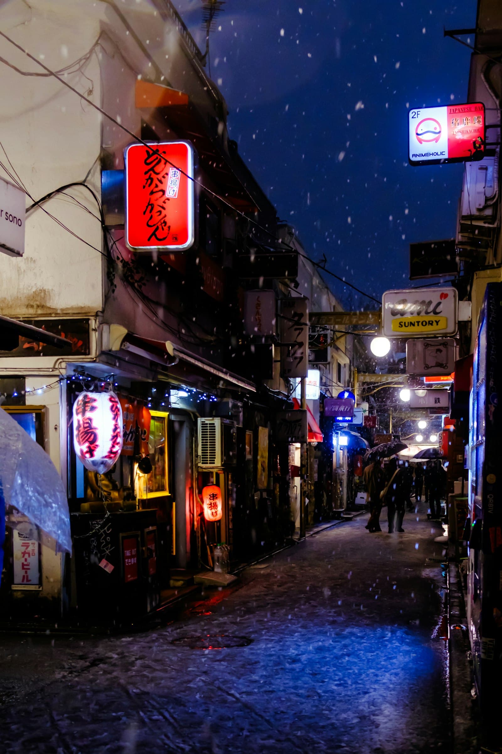 Snow falling at night on a narrow street of small bars in Golden Gai, Shinjuku, Tokyo