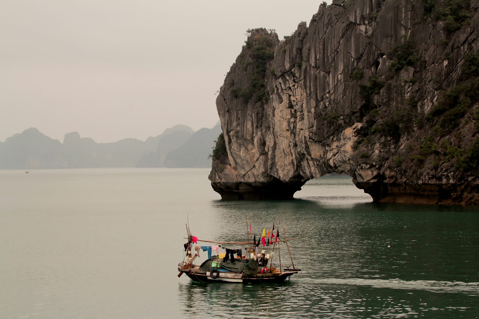 A boat sailing past limestone karst islands in Ha Long Bay, Vietnam
